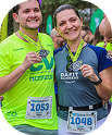 Homem e mulher sorrindo e exibindo suas medalhas de participação em uma corrida.