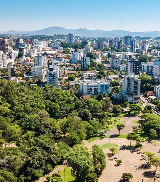 Vista aérea da cidade de Lajeado, com um grande parque arborizado em primeiro plano e os prédios da cidade e morros ao fundo.
